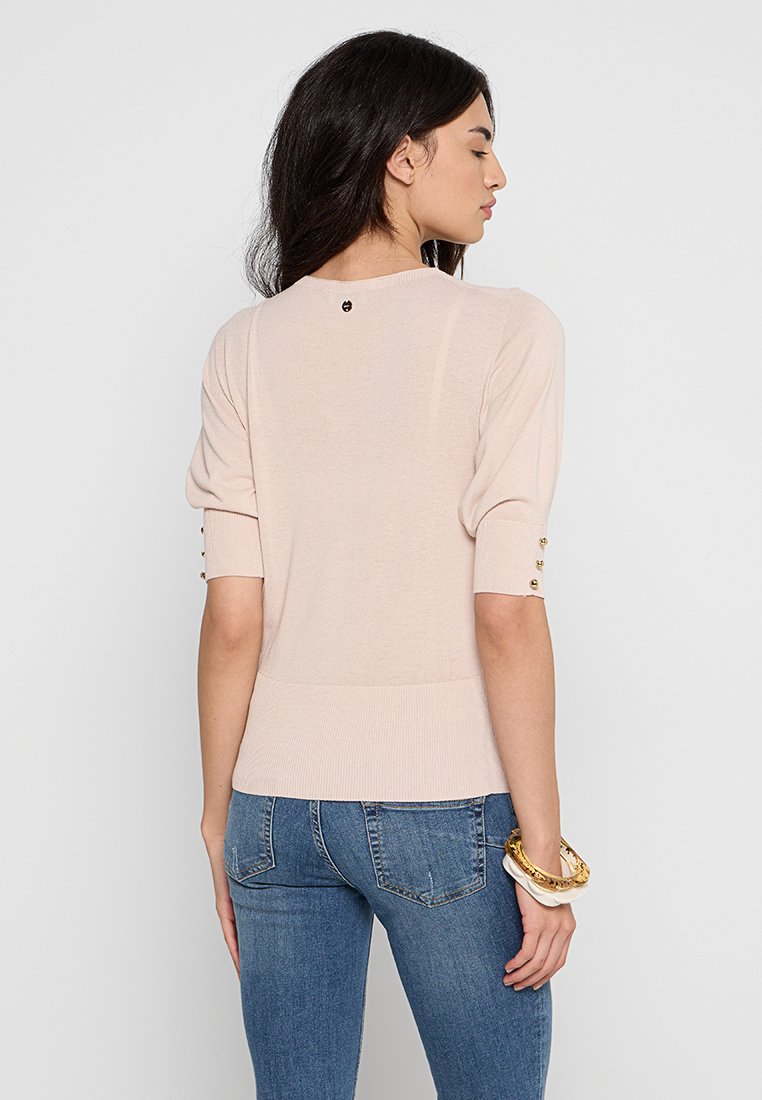 Helles rosa Kurzarm-Sweatshirt mit gepufften Ärmeln, geripptem Saum und goldenen Knopfakzenten an den Bündchen. Glatte Strickoberfläche.