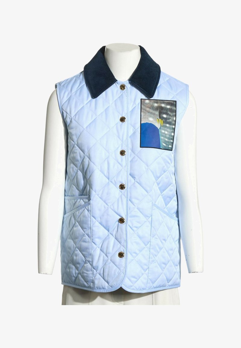 Veste matelassée sans manches bleu clair avec col foncé, boutons dorés sur le devant, deux poches et un petit motif carré sur la poitrine.