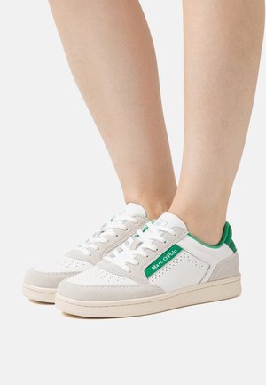 Sneaker bianchi e beige con dettagli verdi e il marchio "Marc O’Polo" indossati a piedi nudi su uno sfondo neutro.