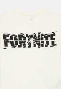 Hvit bomulls-t-skjorte med fet svart grafisk tekst "FORTNITE" med slitt, fragmentert design. Rund hals.