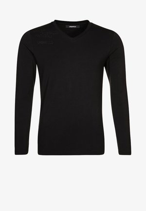 Long-sleeve black shirt with a V-neck design, featuring a textured graphic on the shoulder. Made from a smooth, lightweight fabric.