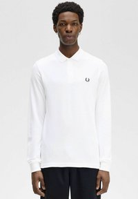 Polo bianco a maniche lunghe con colletto, caratterizzato da un piccolo logo nero ricamato sul lato sinistro del petto; tessuto liscio e design aderente.