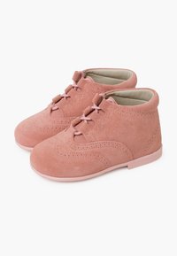 Zapatos de ante rosa con punta redondeada, diseño de cordones, costuras decorativas y un interior suave y acolchado. Suela de goma para mayor tracción.