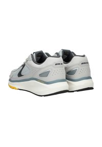 Light gray athletic shoes with mesh and synthetic materials, featuring a black swoosh, gray accents, and yellow details on the sole.