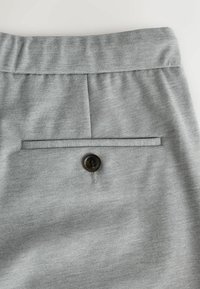 Gray trousers featuring a flat front design, a single back pocket with a black button, and an elastic waistband for comfort.