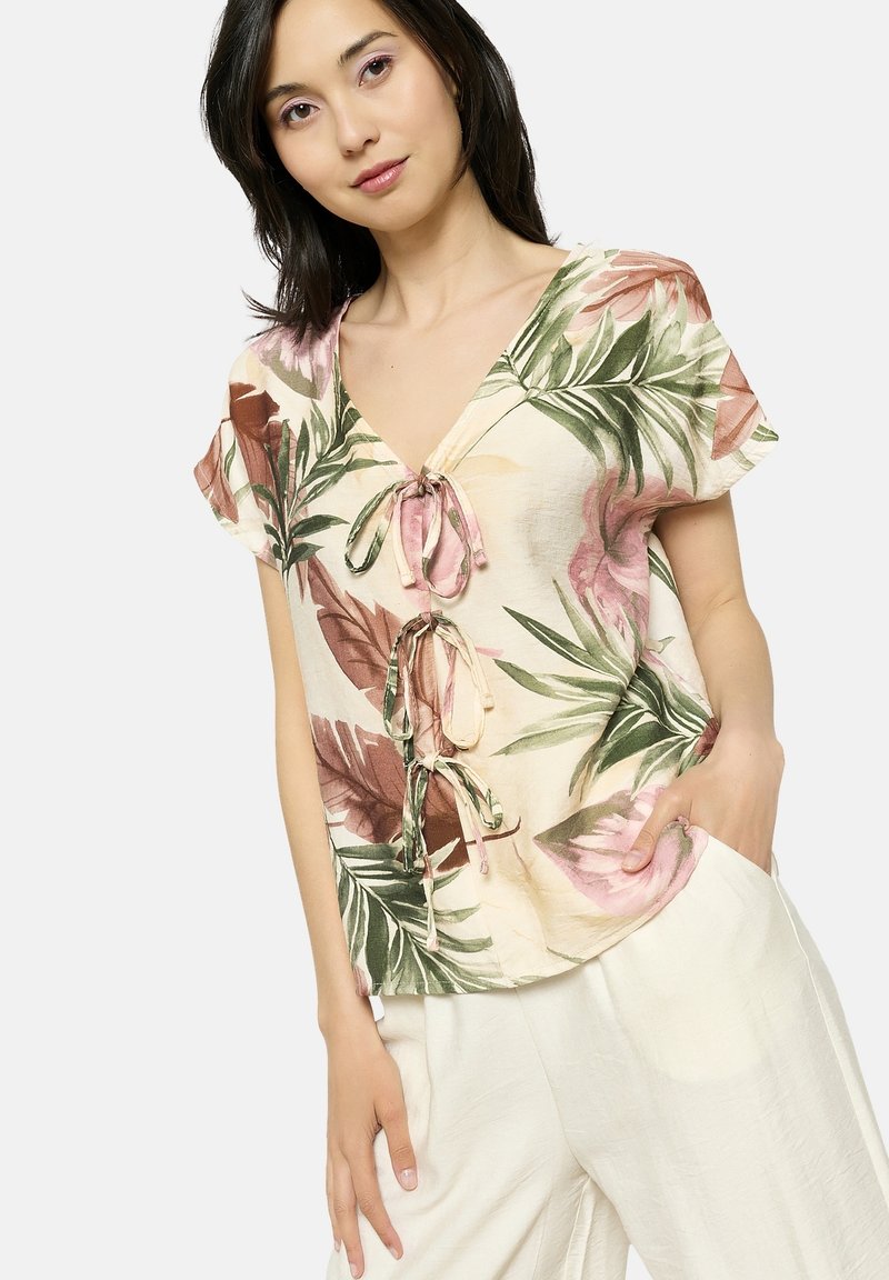 Blusa floreale a maniche corte in tessuto leggero con scollo a V, decorata con foglie verdi e fiori rosa, legata davanti con stringhe abbinate.