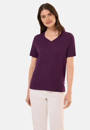 Camiseta de cuello en V morada hecha de tejido suave, con mangas cortas y un corte relajado. Combinada con pantalones de color claro para crear contraste.