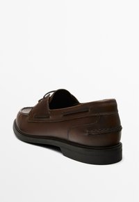Brown leather slip-on shoe featuring a smooth finish, stitched accents, and a rubber sole. The design includes cutouts on the sides.