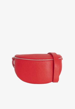 Sac bandoulière en cuir rouge avec une forme incurvée, une finition texturée et une fermeture éclair, porté sur un haut noir à manches longues.