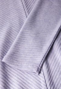 Helles Lavendel gestrickter Stoff mit gerippter Textur. Verfügt über einen gefalteten Ärmel und eine weiche Oberfläche, die einen lässigen Stil betont.