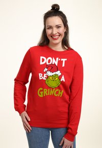 Červená mikina s potiskem Grinche v santovské čepici, s nápisem "NENÍ BUDOUCÍ GRINCH" v tučném bílém a zeleném písmu.