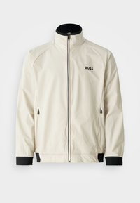 Helle, wasserabweisende Jacke mit hohem Kragen, Reißverschluss vorne, schwarzen Akzenten an den Bündchen und am Saum sowie subtiler Logo-Platzierung auf der Brust.