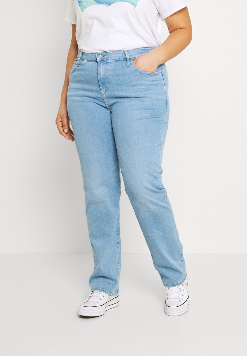 Jeans in denim blu chiaro con vestibilità dritta, caratterizzati da una vita alta, passanti per cintura e classico stile a cinque tasche. Abbinati a sneakers bianche.