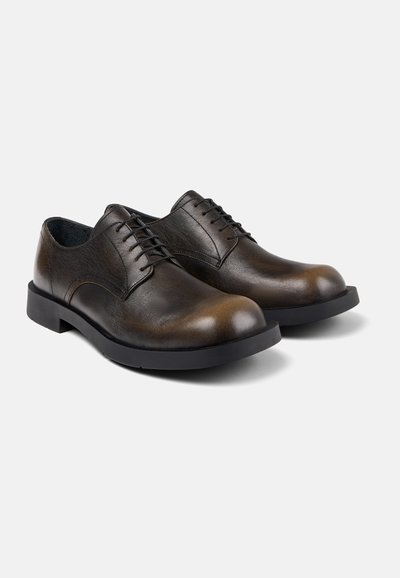 Bruine leren veterschoenen met een gladde afwerking, ronde neus en zwarte rubberen zool; subtiele textuur op de bovenkant en klassiek ontwerp.