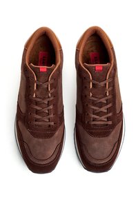 Paar braune Leder- und Wildleder-Sneaker mit Schnürung, gepolstertem Kragen und rotem Zuglasche an den Zungen, von oben auf weißem Hintergrund gezeigt.