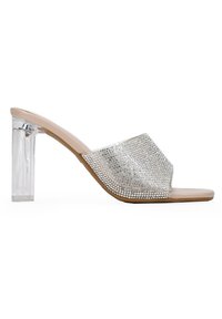 Sandalía de tiras anchas de color nude, con pedrería plateada, tacón cuadrado transparente y punta abierta.