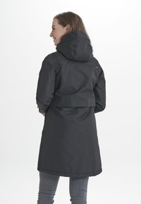 Cappotto impermeabile nero con cappuccio, design di lunghezza intermedia, vita regolabile e tasca a soffietto. Texture liscia con un sottile dettaglio del logo.