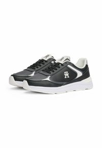 Schwarze und graue Sportschuhe mit einer strukturierten Lederoberfläche, weißen Akzenten, traditioneller Schnürung und einer gepolsterten Sohle. Großes Logo auf der Zunge.