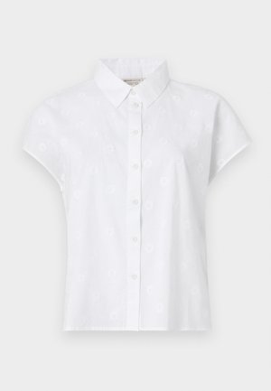 Valge lühikeste varrukatega särk, mis on valmistatud kergest kangast, millel on nööbiga esiosa ja õrnad lillemotiivid üle kogu särgi.