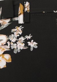 Zwarte stof met een bloemmotief in lichtroze, oranje en witte bloemen. Getextureerd oppervlak met een riemlus en stikseldetails.