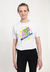 Vitt bomullströja med en färgglad björngrafik i grönt, rosa och lila, med texten "Vi klarar det här" och gula stjärnaccenter.