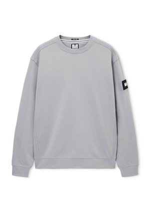 Jasnoszara bluza z długim rękawem i okrągłym dekoltem, z prążkowanymi mankietami, dołem oraz czarną prostokątną naszywką na lewym rękawie.