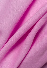 Lichtroze, gestructureerde stof gedrapeerd in plooien, met een glad oppervlak en subtiele glans, typisch voor lichtgewicht linnen of katoen.