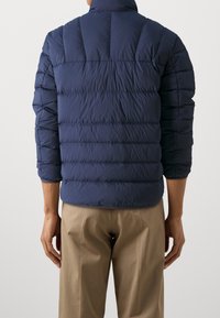 Donkerblauwe pufferjas met gestikte horizontale panelen en hoge kraag, voorzien van een lichtgewicht, gladde textuur en licht aansluitend ontwerp.