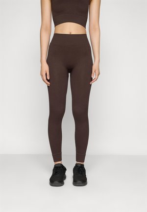 Crop top marron à côtes et leggings taille haute assortis, dotés d'une coupe ajustée et d'une texture lisse, associés à des chaussures de sport noires.