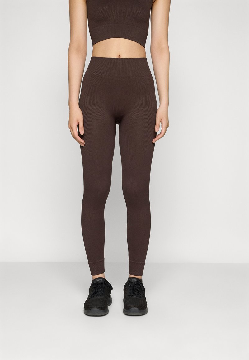 Brun ribbet crop top og matchende høytliv leggings, med en tettsittende design og glatt tekstur, kombinert med svarte treningssko.