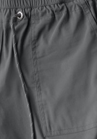 Shorts gris en tissu léger, dotés d'une taille élastique, d'un cordon de serrage et d'une poche latérale avec un rabat rectangulaire.