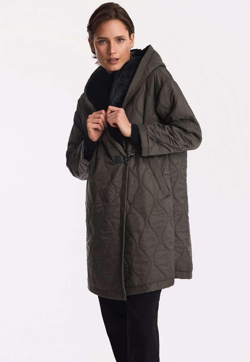 Pikowany, oliwkowozielony płaszcz z kapturem, z teksturowanym wzorem, odpinaną czarną podszewką i wcięciem w talii z detalem klamry.