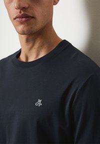 Dark blue short-sleeve t-shirt made of cotton with a round neckline, featuring a small white "M OP" logo on the left side of the chest.
