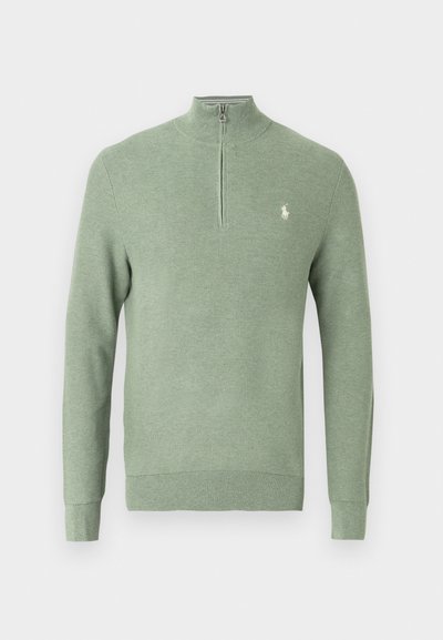 Zöld kötött pulóver negyed cipzárral, bordázott mandzsettákkal és alsó szegéllyel, bal oldali mellrészen kis hímzett logóval. Texturált anyag.