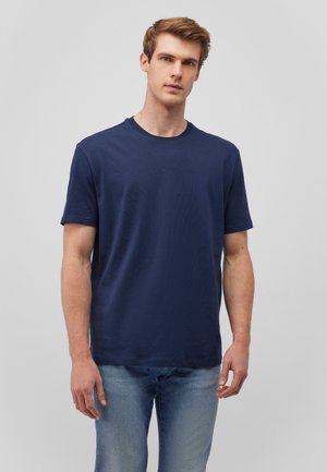 Marineblaue Baumwoll-T-Shirt mit Rundhalsausschnitt und kurzen Ärmeln; glatte Textur und lockere Passform; kombiniert mit hellblauen Jeans.