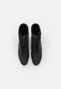 Černé kotníkové boty vyrobené z hladké kůže, s šněrovacím designem, zaoblenou špičkou, polstrovaným límcem a jemným logem na stélce.