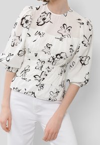 Weißes Bluse mit schwarzem Blumenmuster, halbtransparenten Puffärmeln und gerafftem Bund. Glatte Textur, Rundhalsauschnitt und fließende Silhouette.