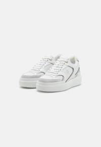 Hvite sneakers med en kombinasjon av skinn og mesh-materialer. Tykk såle, grå detaljer og lavt design med runde lisser.