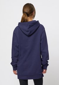 Sudadera oversized azul marino con un acabado texturizado, mangas largas y capucha con cordón. Presenta un dobladillo recto y puños de canalé.