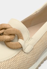 Μπεζ παπούτσι χωρίς κορδόνια με υφαντή υφή, λεία δερμάτινα στοιχεία και διακοσμητικό πλεκτό κόμπο σε αντίθετο ταμπά χρώμα.