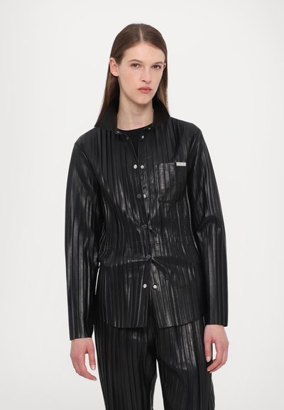 Schwarze plissierte Jacke aus Kunstleder mit hohem Kragen, Druckknöpfen und einer Vordertasche. Glatte Textur und glänzendes Finish.