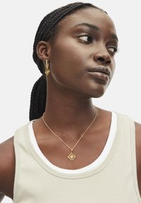 Gouden sieradenset met een diamanten hangerketting en bijpassende creolen. De textuur is glad met ingewikkelde details.