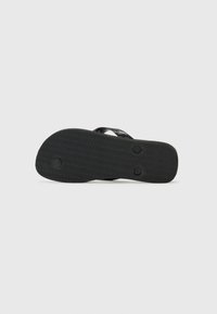Black rubber flip-flop sandal with textured sole and three circular plug attachments visible on the bottom against a plain background.
