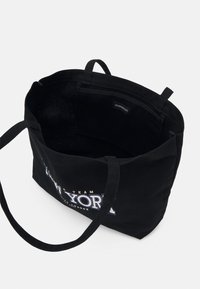 Sac fourre-tout noir avec de longues anses, affichant l'inscription « YORK » sur le devant, ouverture supérieure et poche intérieure avec étiquette de marque.