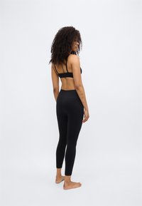 Schwarzer Sport-BH und Leggings aus elastischem Stoff mit hohem Bund und nahtlosem Design für Komfort und Passform.