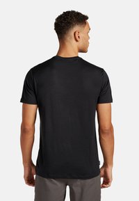 Schwarzes T-Shirt mit kurzen Ärmeln aus einem weichen, leichten Stoff, featuring einen klassischen Rundhalsausschnitt und einer lockeren Passform. Rückansicht gezeigt.
