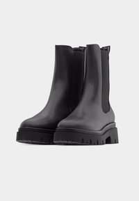 Musta nahast pahkluu saapad elastsete küljeplokkidega, paksu kontsaga, ümarate ninaosaga ja siledapinnalised. Ei ole nähtavaid kinnitusi ega mustreid.