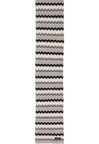 Sciarpa morbida e lunga con righe zigzag alternate in bianco, nero e tonalità di grigio, dotata di una piccola etichetta rettangolare del marchio.