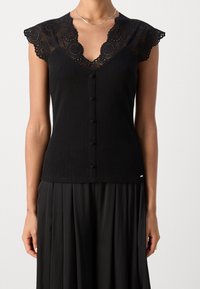 Černý žebrovaný top bez rukávů s krajkovým lemem kolem výstřihu a šesti knoflíky vpředu. Hladká textura a přiléhavý střih, v kombinaci s černou plisovanou sukní.