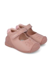 Zapatos infantiles de color rosa claro, hechos de material suave, con puntera redondeada, correa ajustable y diseño de búho en relieve en la zona de la puntera.
